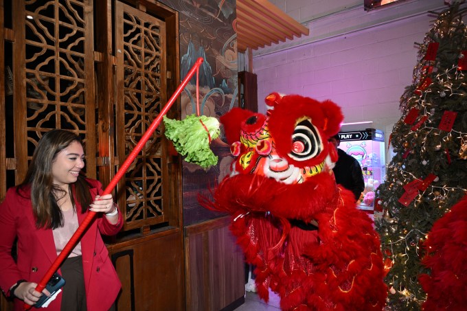 State Sen. Kristen Gonzalez "feeds" a ceremonial lion at Chi Chicken. Photo: Ramy Mahmoud.